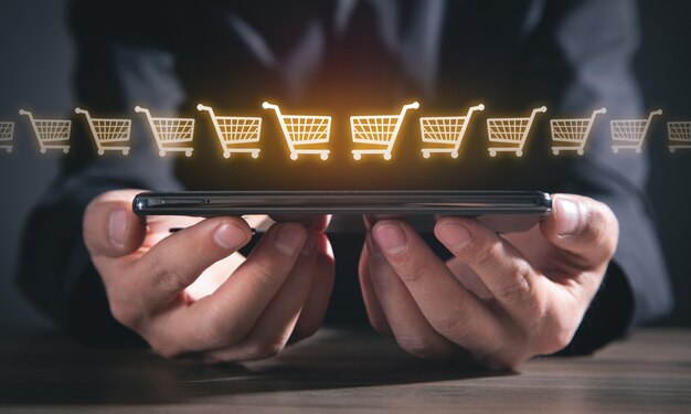 Businessman holding smartphone with a shopping carts.