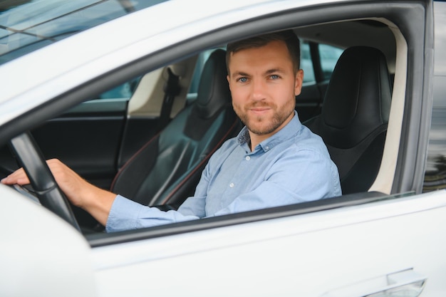 Businessman holding steering wheel while driving modern electric car on the street road Confident man driving expensive car Driver Turning Steering Wheel In Luxurious Auto On Trip