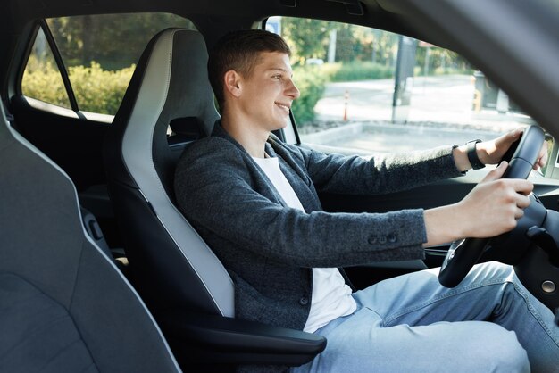 Businessman holding steering wheel while driving modern electric car on the street road confident