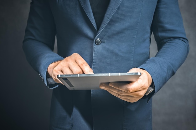 Businessman holding tablet computer on dark background Business growth planing and strategy concept copy space