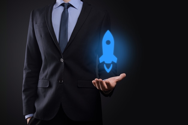 Businessman holding tablet and icon rocket is launching and soar flying out from screen