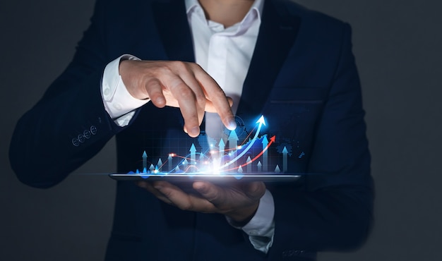 Businessman holding tablet with  growing virtual hologram of statistics graph and chart