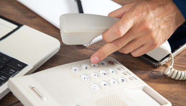 Businessman holding telephone receiver at the office table