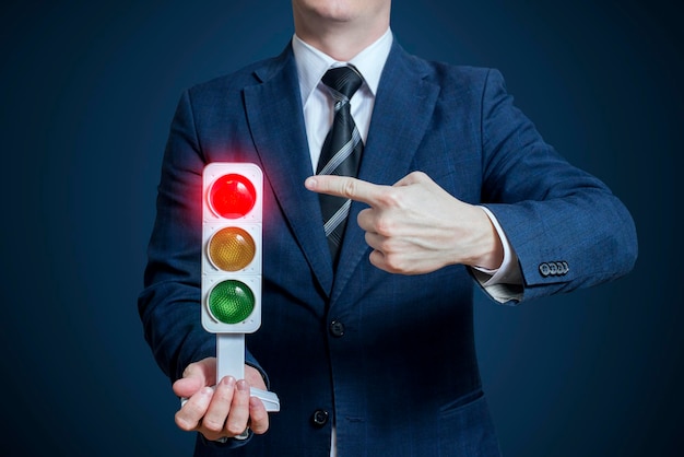 Businessman holding a traffic light with red light on business concept