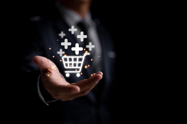 A businessman holding a virtual shopping basket icon with a plus sign to add or receive an order is depicted in this technologybased company concept for online shopping