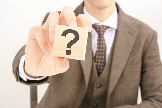 Businessman holding wooden block with the question mark