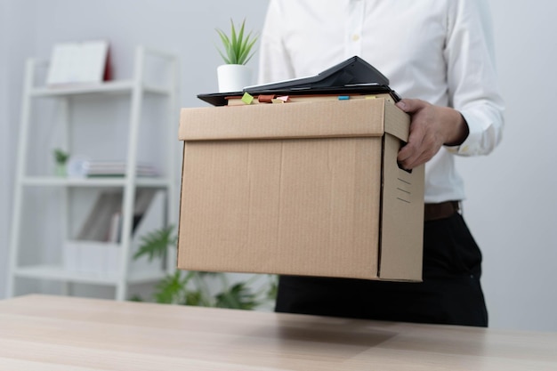 A businessman holds a box for personal items after sending a resignation letter to an executive or manager Include information about resignation and vacancies and job changes