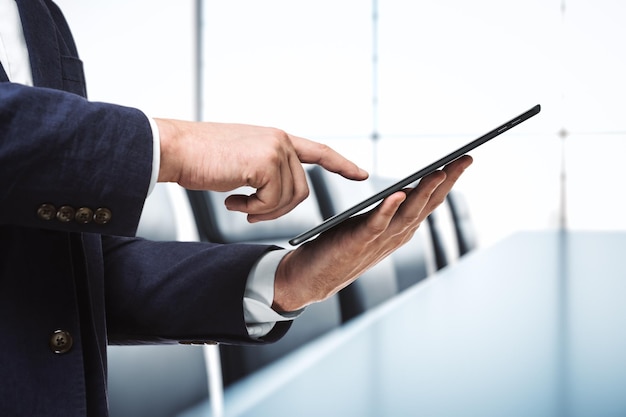 Businessman holds digital tablet and clicks on screen in modern office close up Search concept