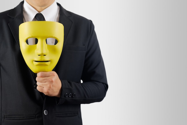 Businessman holds the mask in hand on gray