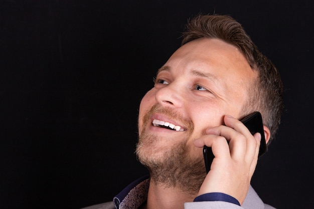 Businessman holds a mobile phone in his hands and expresses emotion from the conversation