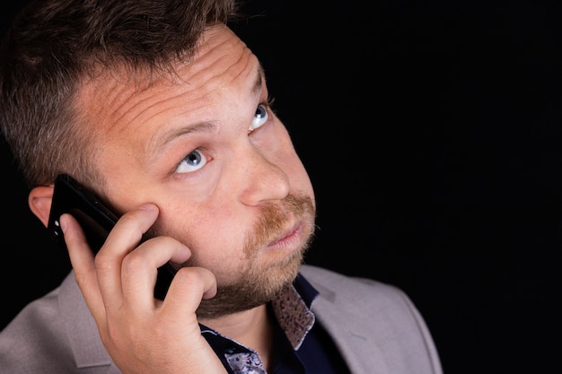 Businessman holds a mobile phone in his hands and expresses emotion