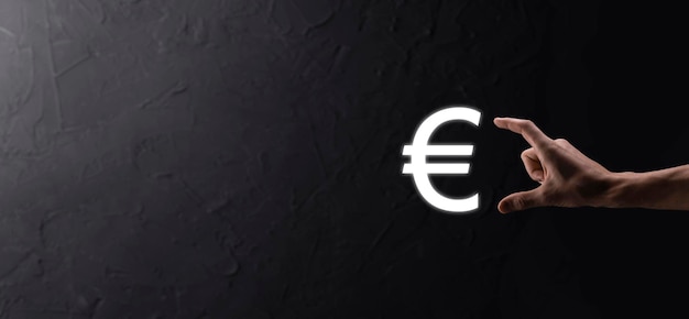 Businessman holds money coin icons EUR or Euro on dark tone backgroundGrowing money concept for business investment and finance