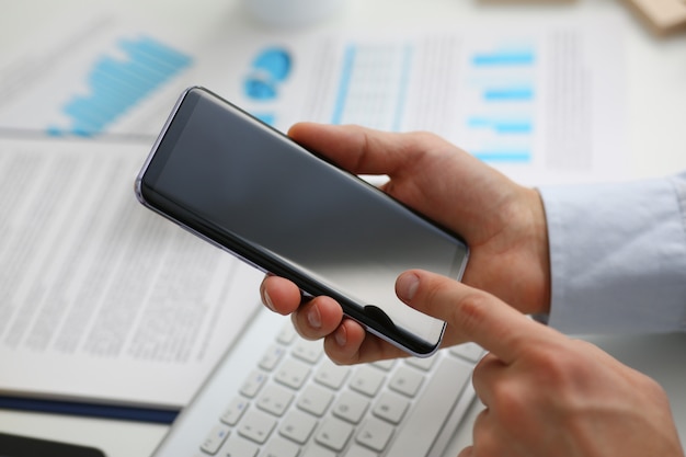 A businessman holds a new smartphone in his hand