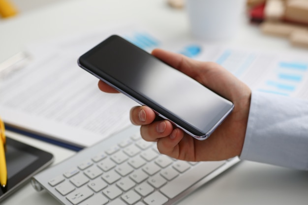 A businessman holds a new smartphone in his hand