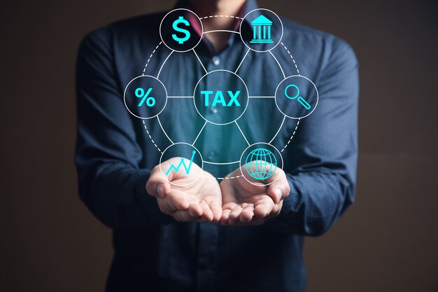 Businessman holds a tax icon in his hand