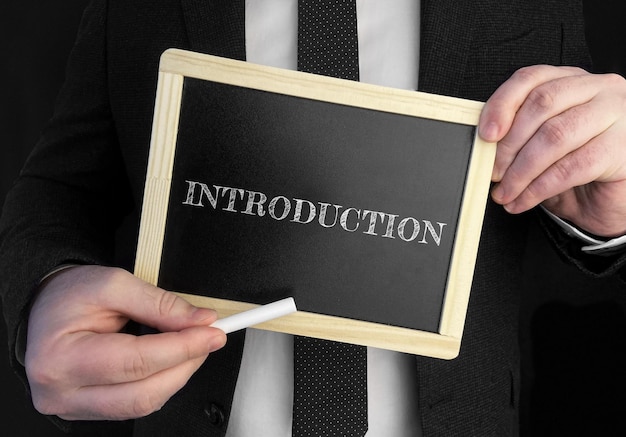 A businessman holds up a chalkboard with text Introduction