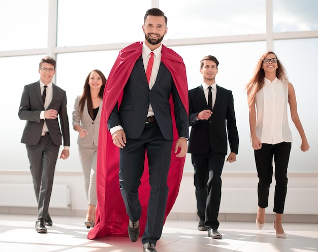 Businessman is a superhero stepping ahead of his business teamphoto with copy space