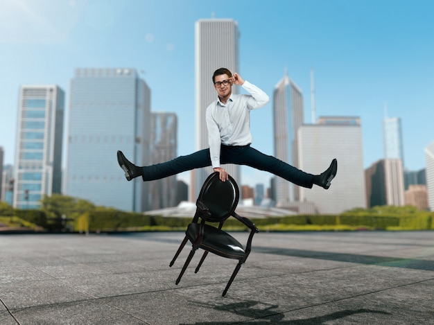 Businessman jump over chair against skyscrapers