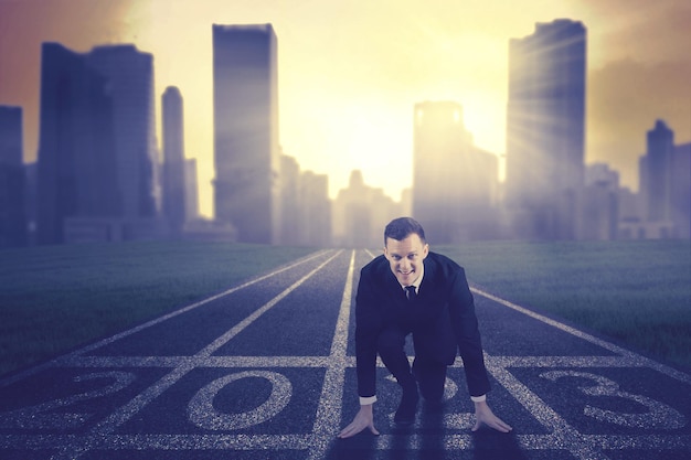 Businessman kneel on start line with 2023 number