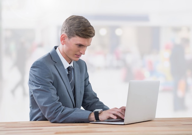 Businessman on laptop in bright shopping mall