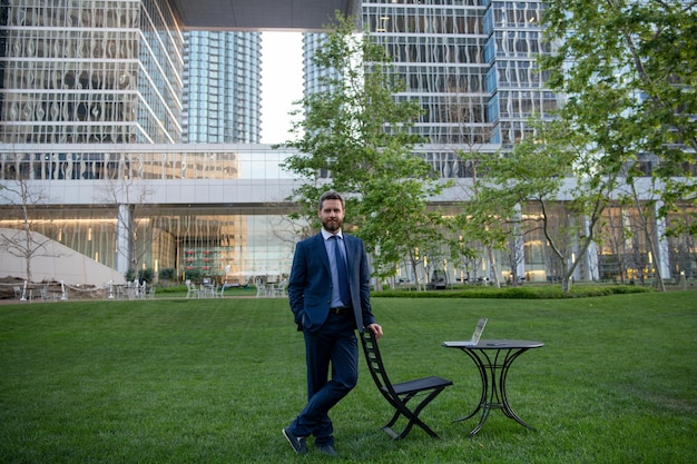 Photo businessman on large grass field near modern office building business man in park of megapolice