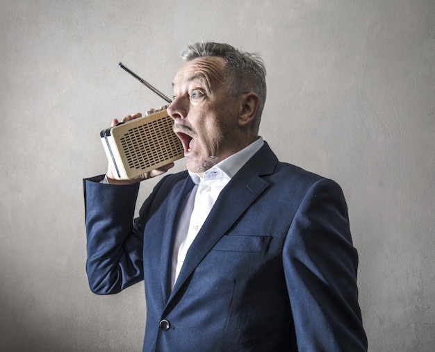 Businessman listening to the radio making strange expressions