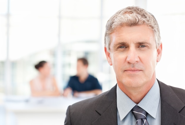 Businessman looking at the camera while his team is working 