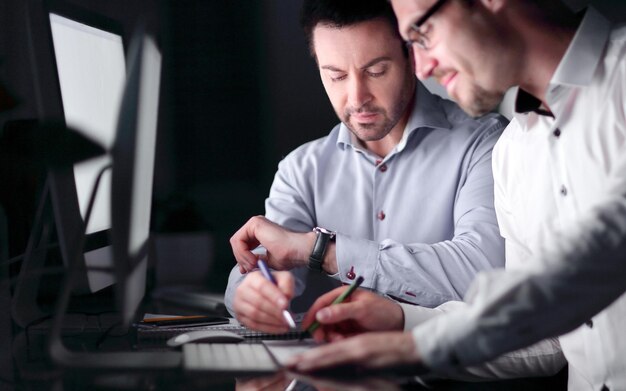 Photo businessman looking at his watch while sitting at his desk