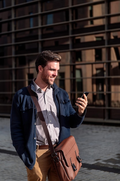 Businessman looking phone by an office building