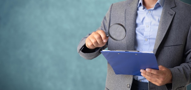 Businessman looks at papers with a magnifying glass