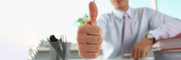 Businessman makes thumbs up gesture closeup successful career