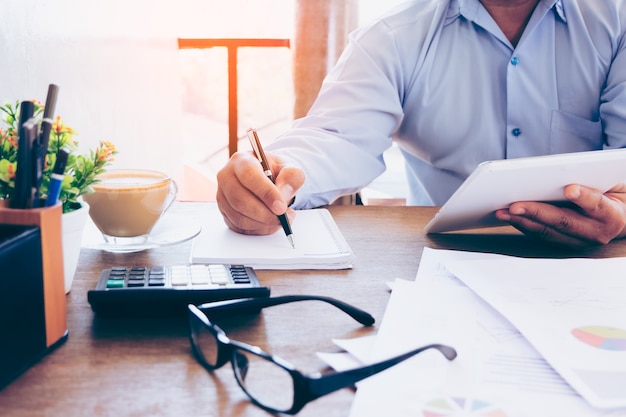 Businessman making notes on the paper at window edge in his office