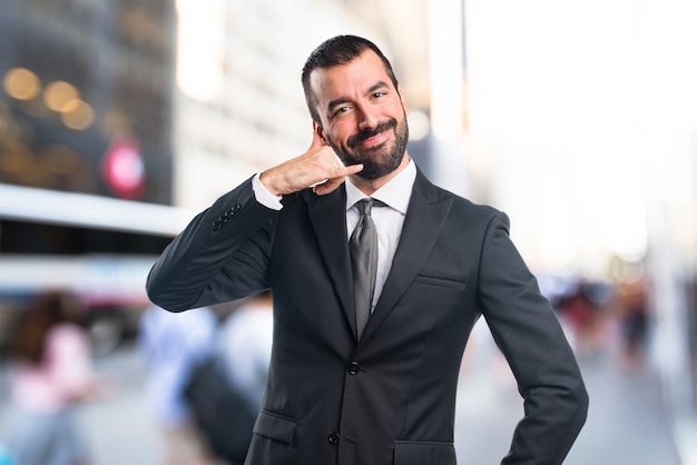 Businessman making phone gesture on unfocused background