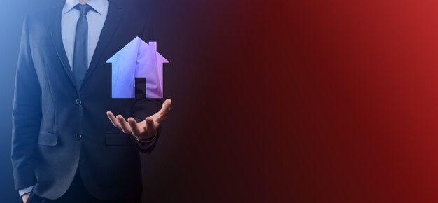 Businessman male hand holding house icon on blue background. Property insurance and security concept.Real estate concept.Banner with copy space.