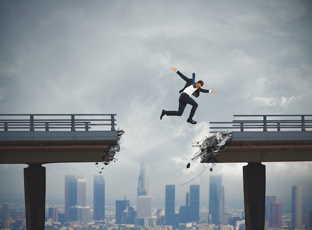 Businessman passes a broken bridge with a big jump