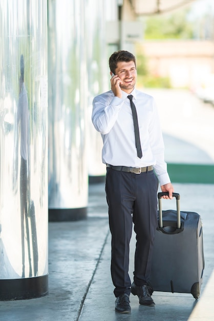 The businessman phone and walk with a suitcase