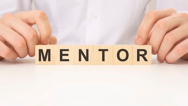 Businessman placing the wooden cubes with the word mentor business program or meeting agenda concept