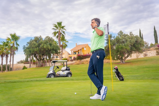 Businessman playing golf and answering the phone for a work emergency