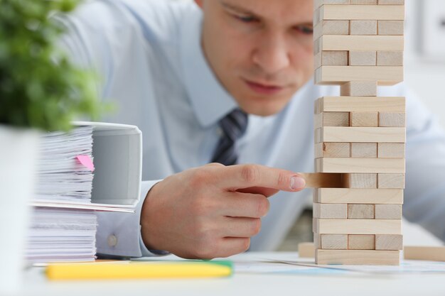 Businessman plays in a strategy of jenga hand