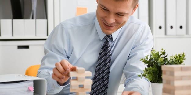 Businessman plays in a strategy of jenga hand