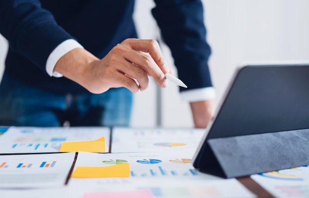 Businessman pointing digital pens to tablet and working on the table and financial documents in office. 