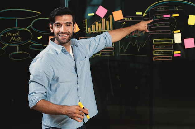 Businessman pointing at marketing statistic while looking at camera tracery