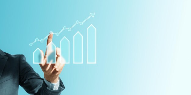 Photo businessman pointing at upward trending graph on blue background