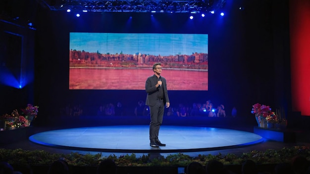 Businessman presenting on stage with large screen