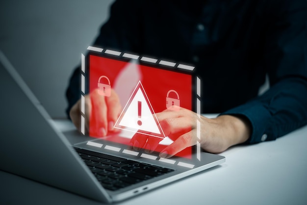 Businessman programmer developer using laptop computer with triangle caution warning sign system hacked on computer network cybersecurity vulnerability