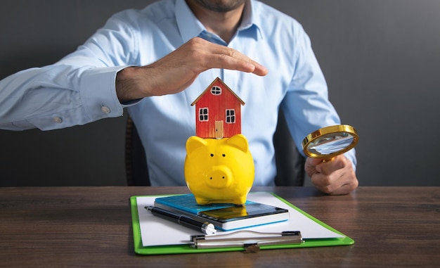 Businessman protect piggy bank with a house model