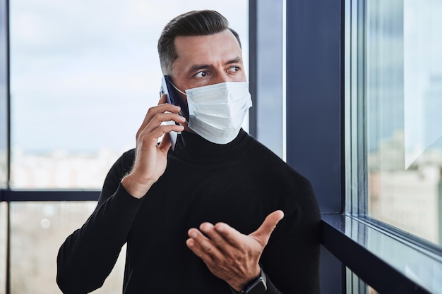 Businessman in a protective mask communicating on a smartphone