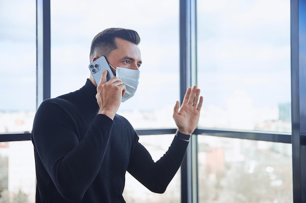 Businessman in a protective mask communicating on a smartphone