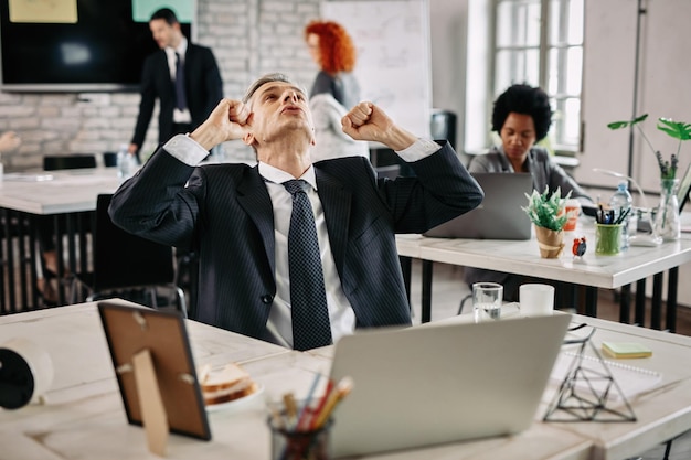 Businessman punching the air and looking up while celebrating success in the office