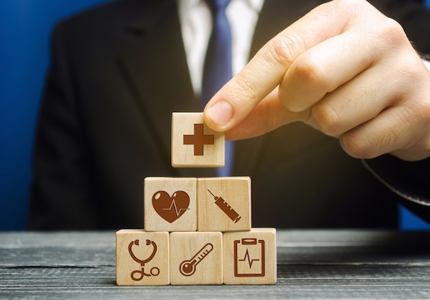 Businessman puts wooden blocks with the image of medical symbols. Healthcare and medical